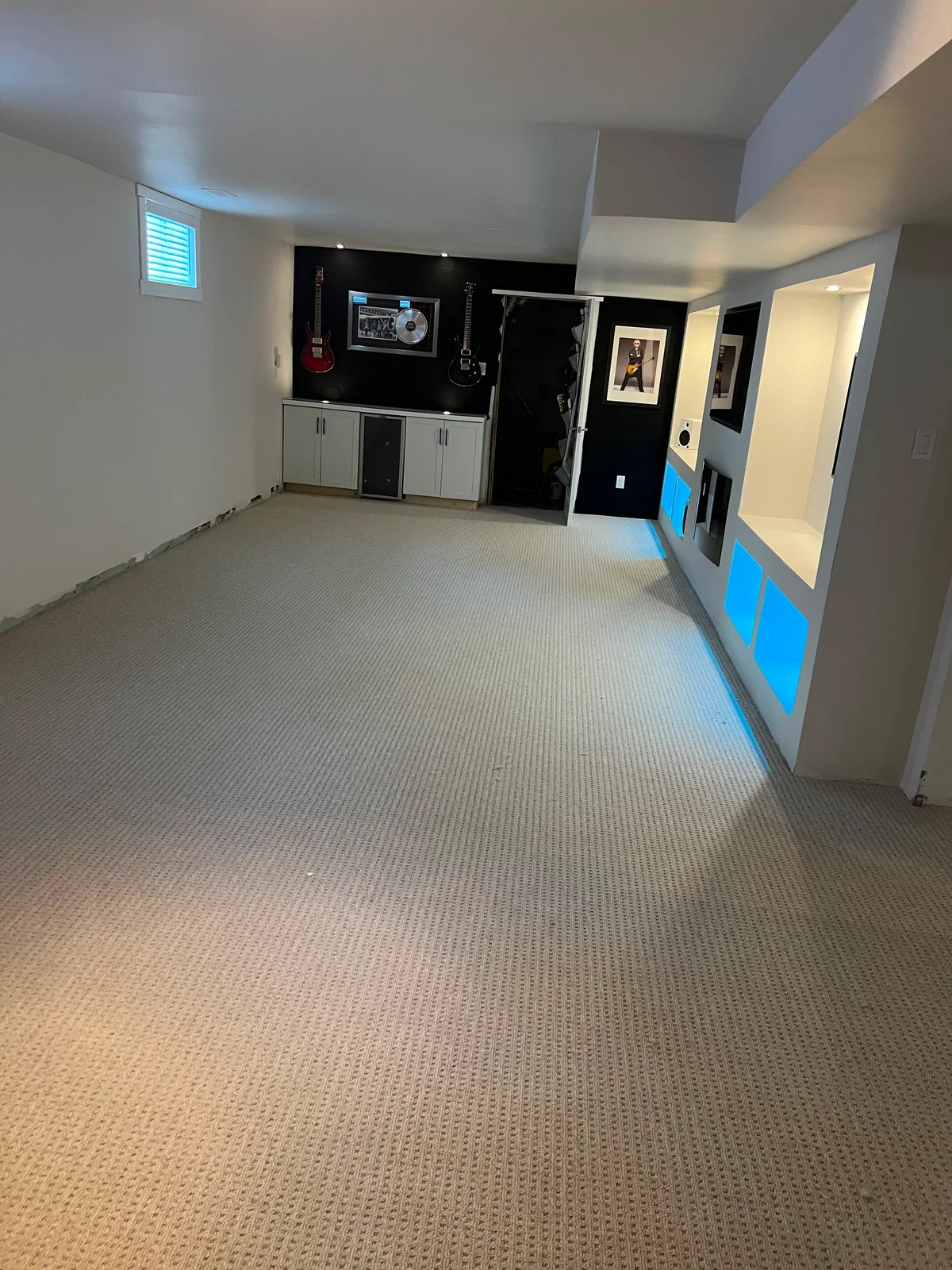 The room at the end of the same basement, carpeted in the same cream loop and taken right up to the cabinets