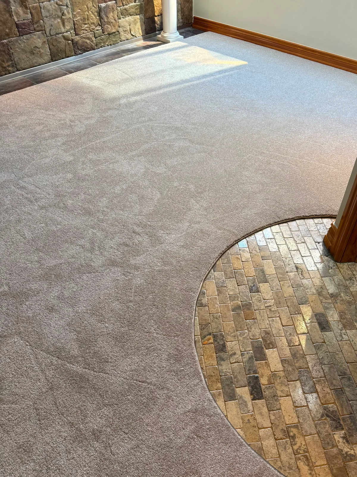 Broadloom carpet cut in one long sweeping curve where it meets a brick paved entry, the cut sitting tight to the brick the whole way round