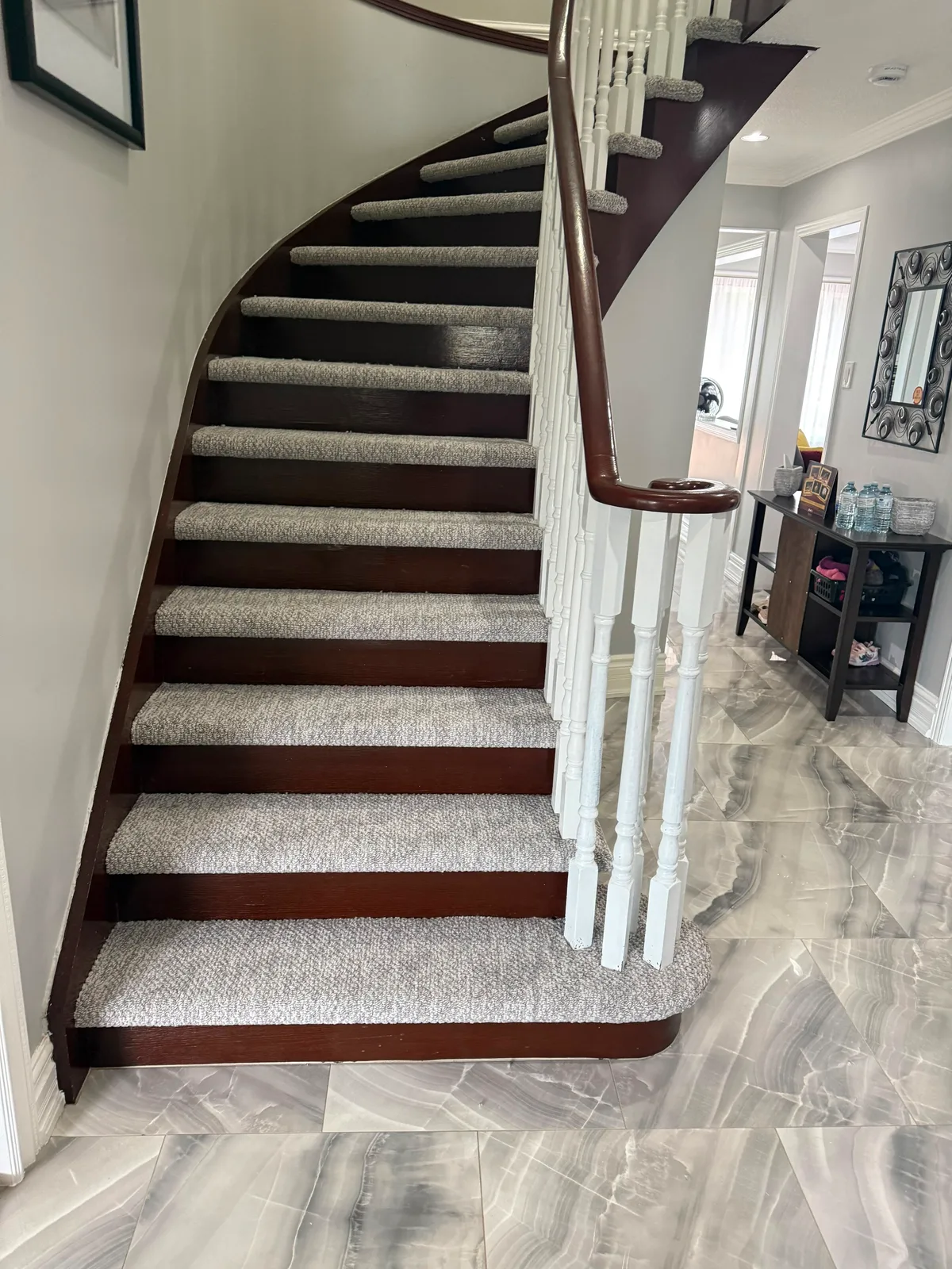 The curved staircase from the foot, showing the carpet inset held to an even margin on every tread