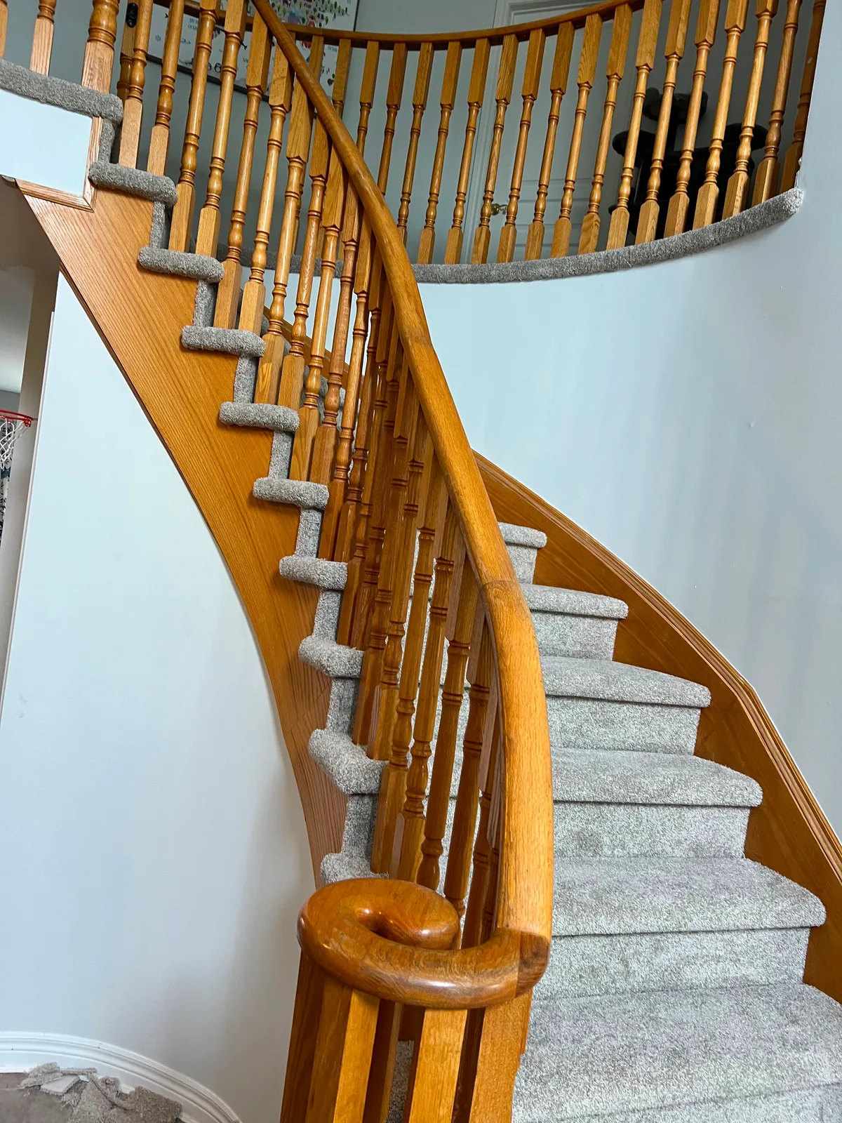 The finished curved staircase carpeted around its full sweep, cut tight to the oak stringer on every winder