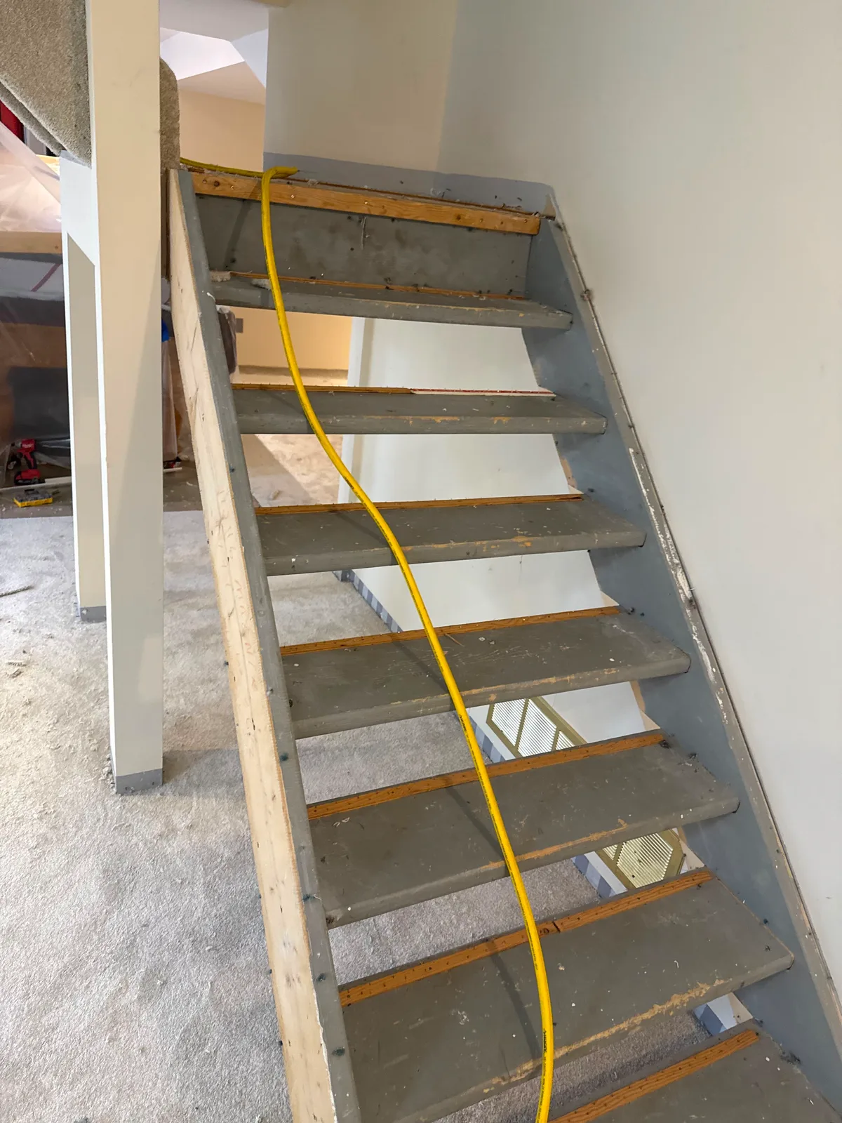 Open riser basement stairs stripped back to bare treads, with gripper rods fitted along the back of every step