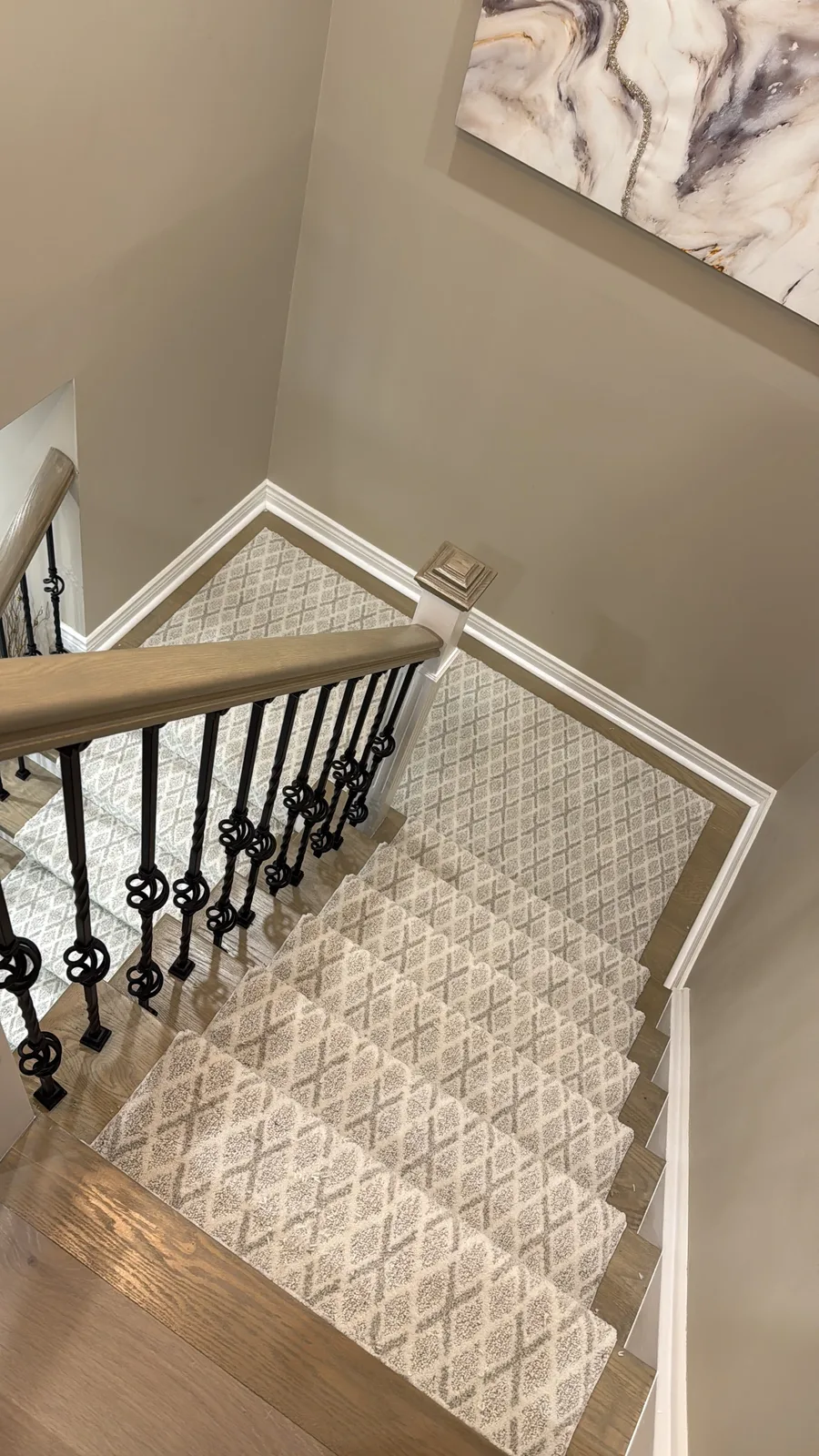 A cream carpet in a grey lattice pattern carried down a turning staircase, the repeat kept straight all the way through the turn